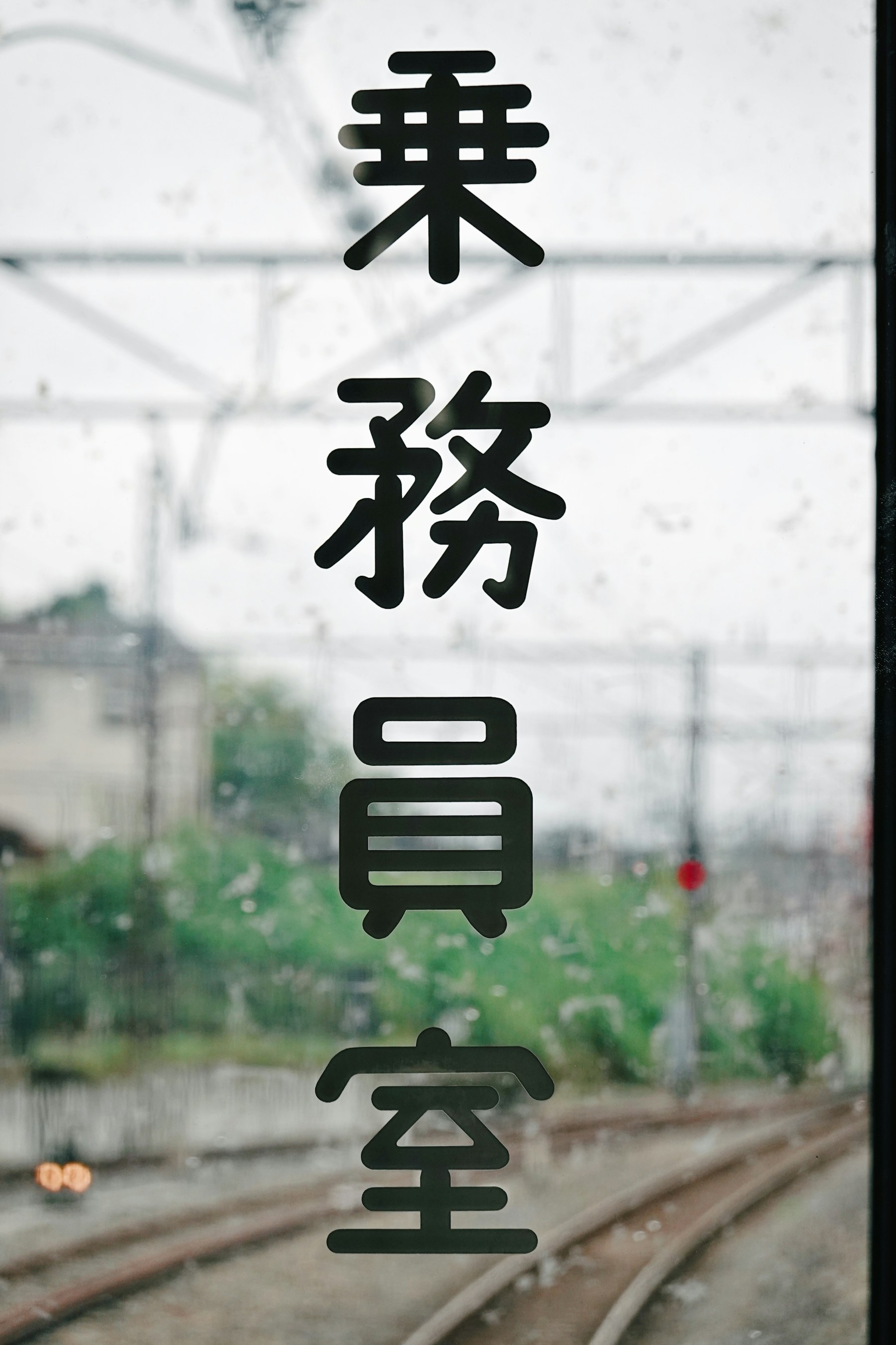 Texto japonés en una ventanilla de tren bajo la lluvia